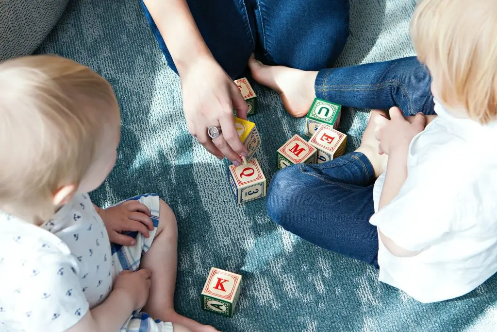 Bild welches eine Kitamitarbeiterin beim spielen mit U3 Kindern zeigt.